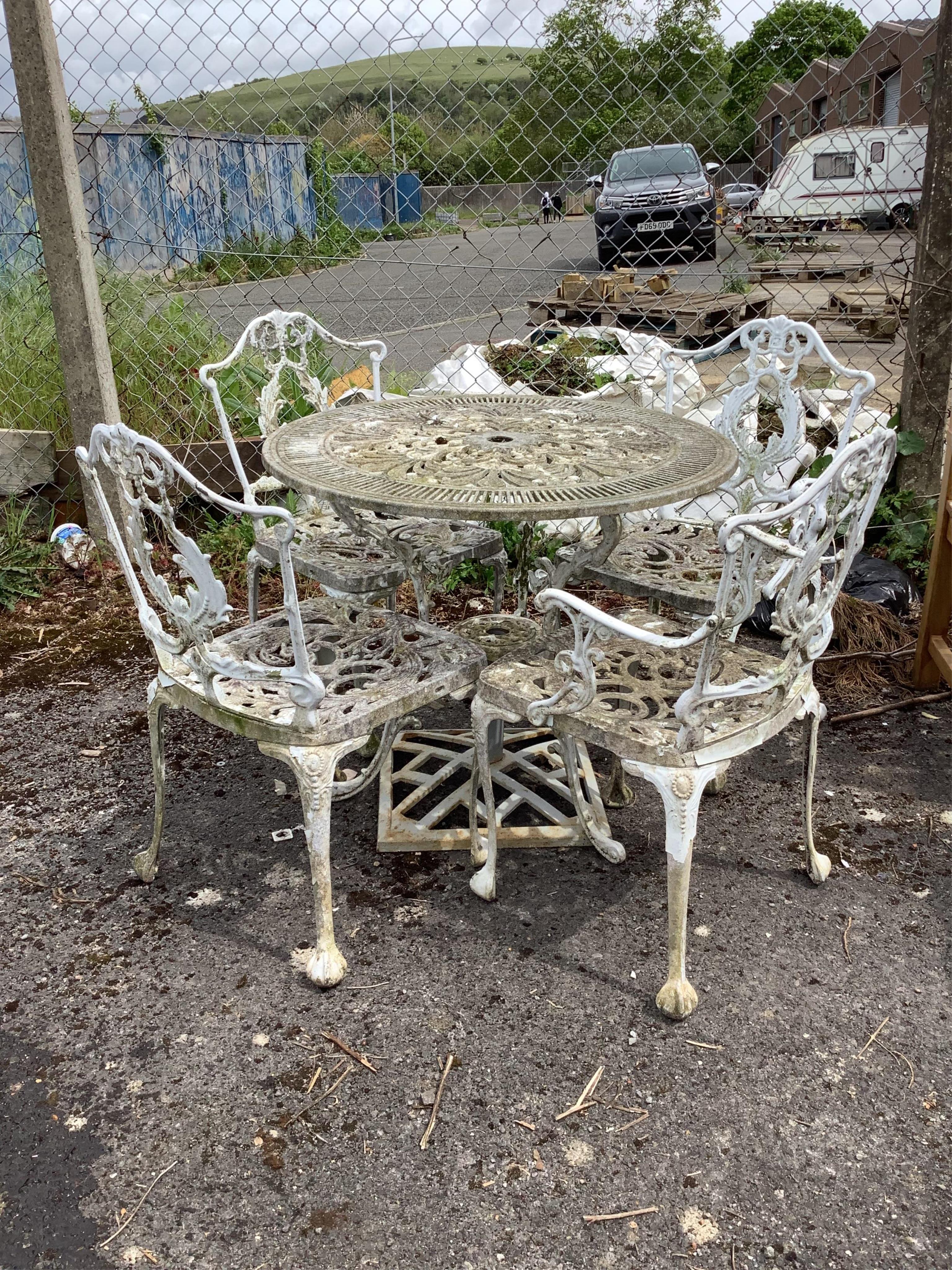 A circular Victorian style painted aluminium garden table, diameter 80cm, height 69cm, together with four aluminium garden elbow chairs